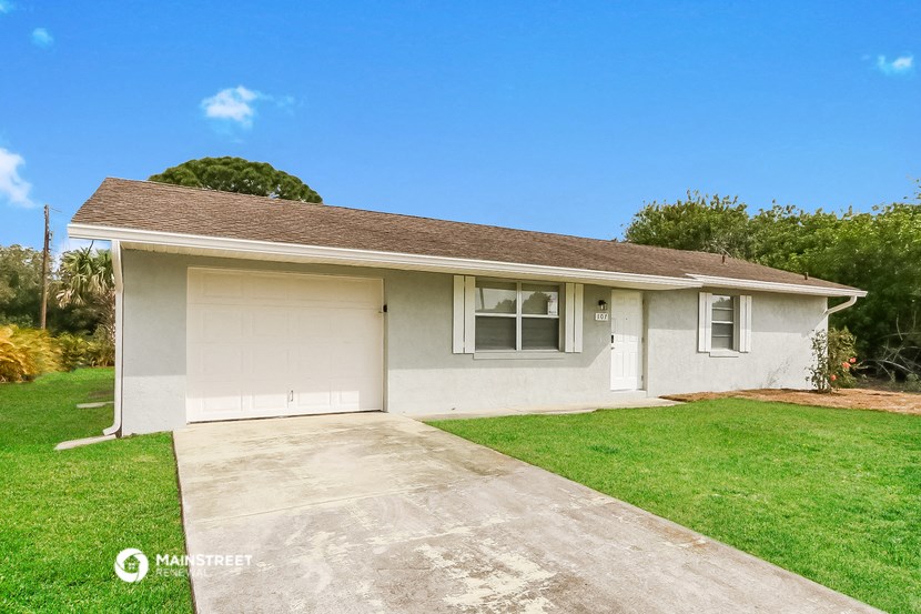 a small white house with a driveway and grass