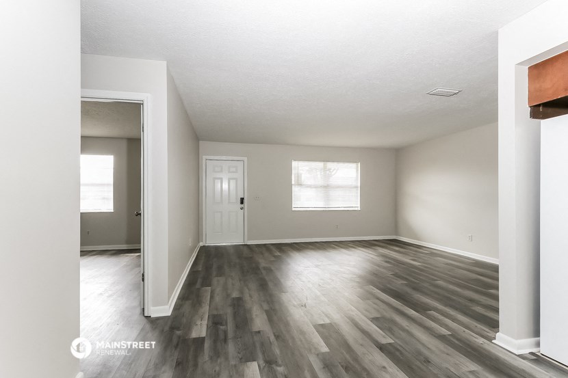 the spacious living room with hardwood flooring and white walls