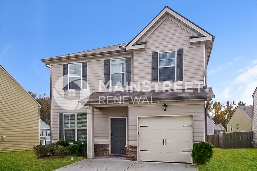 a single story house with a garage on a green lawn