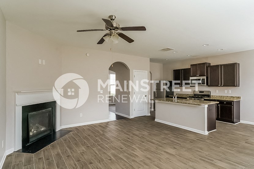 a living room with a fireplace and a kitchen