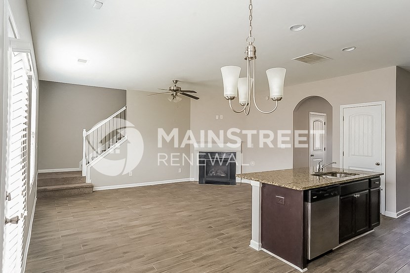a living room with a kitchen and a staircase