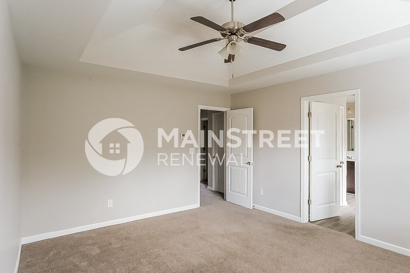 a living room with a ceiling fan and a door to a hallway