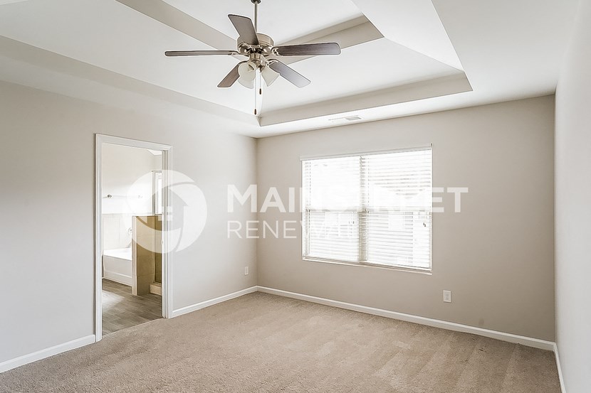 a living room with a ceiling fan and a door to a bedroom