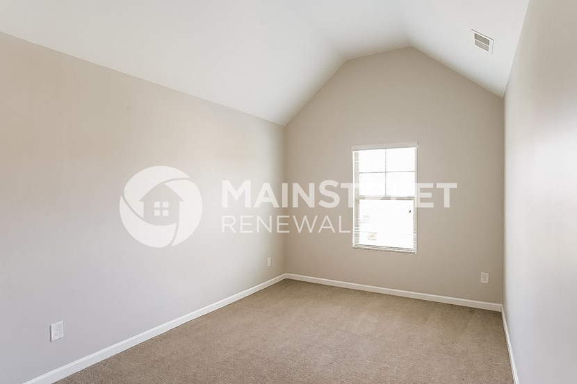 a master bedroom with a vaulted ceiling and beige carpet