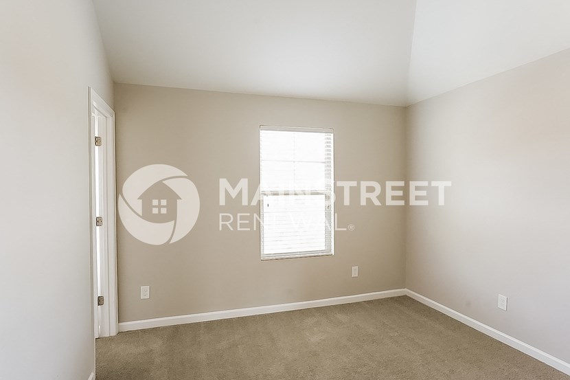 a bedroom with a carpeted floor and a window