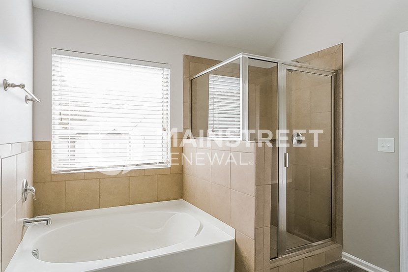 a bathroom with a tub and a shower and a window