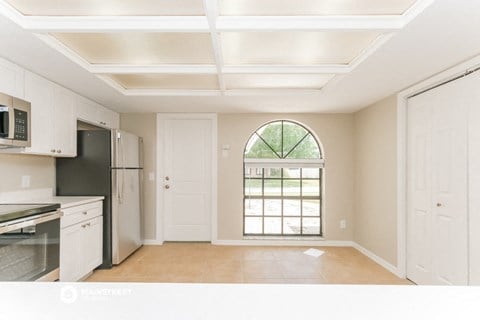 a kitchen with an arched window and white cabinets