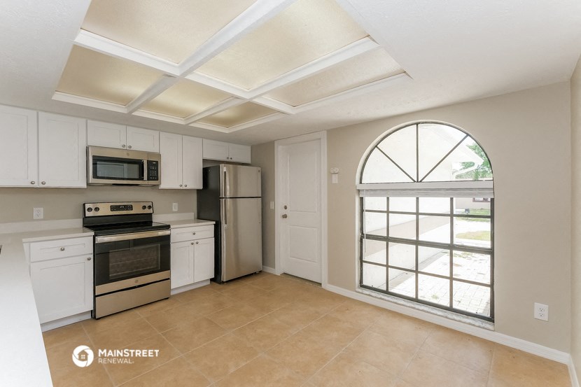a kitchen with white cabinets and appliances and a large window