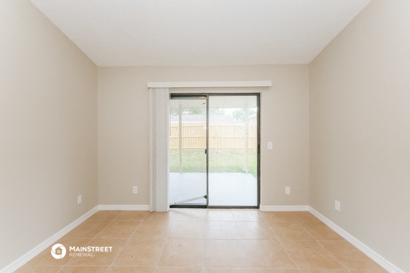 a spacious living room with sliding glass doors to a patio