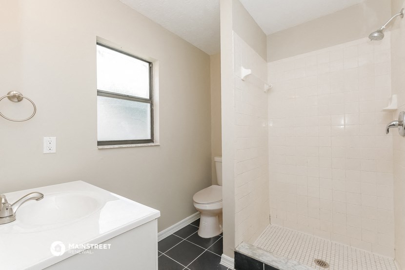 a bathroom with a shower sink and toilet and a window