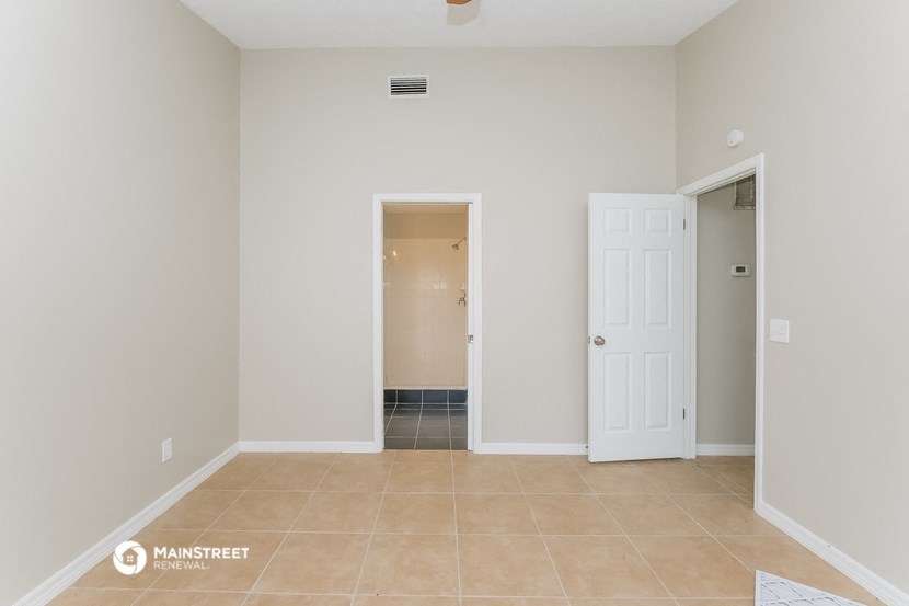 an empty living room with a door to a hallway and a closet