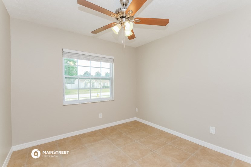 an empty room with a ceiling fan and a window