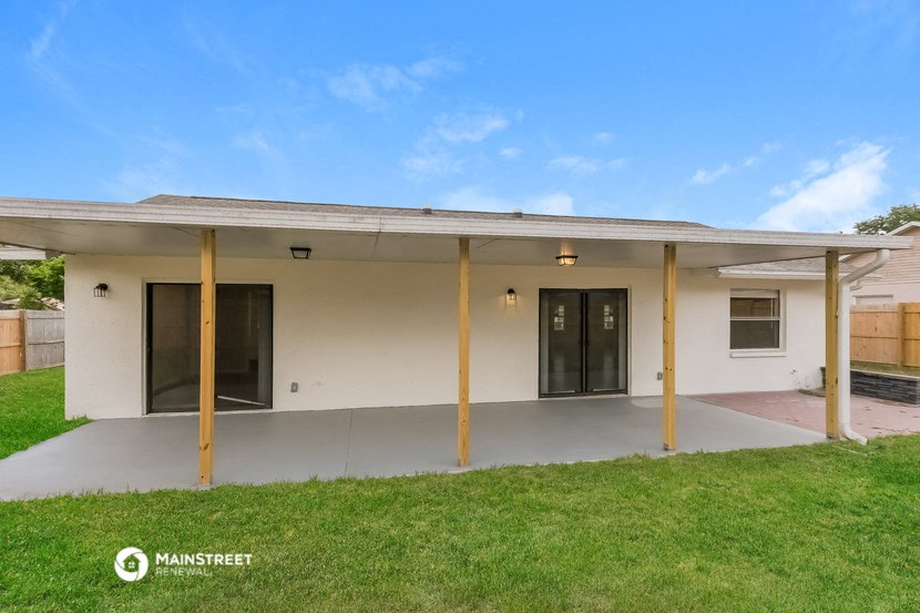 the backyard of a house with a covered porch and a lawn