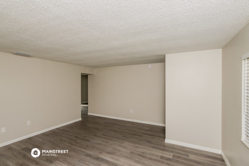 the spacious living room with wood flooring and white walls