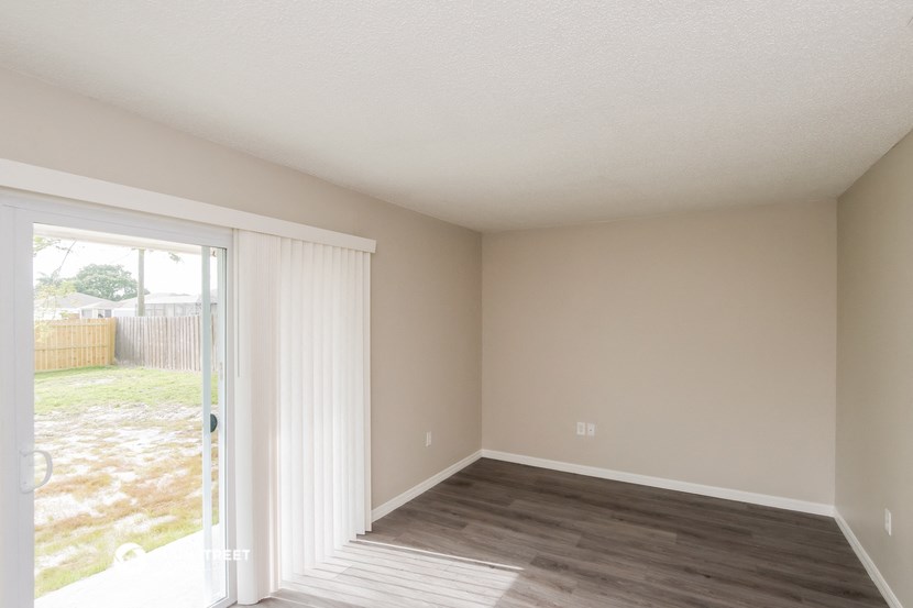 an empty living room with a sliding glass door to a yard