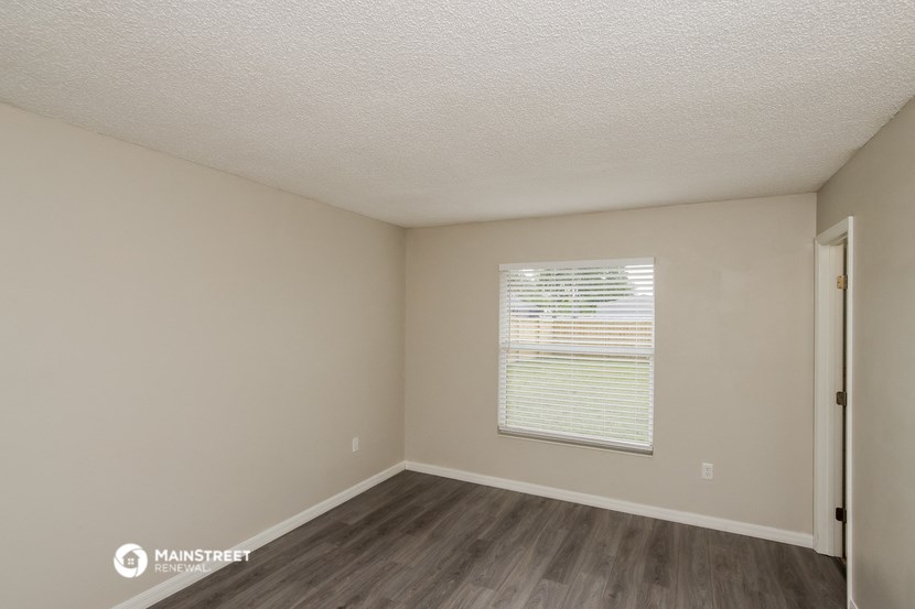 the interior of an empty room with wood flooring and a window