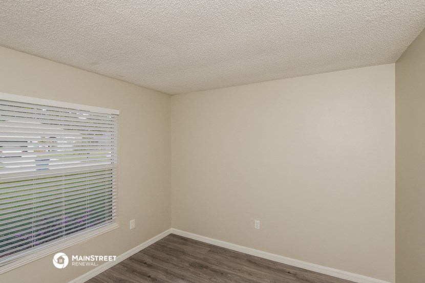 the interior of an empty room with a large window and wooden floors