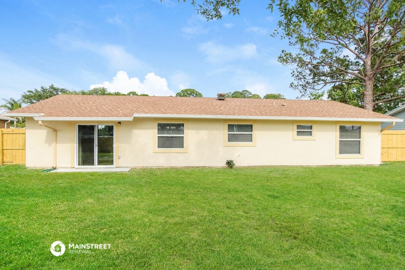 a yellow house with a green lawn and a tree
