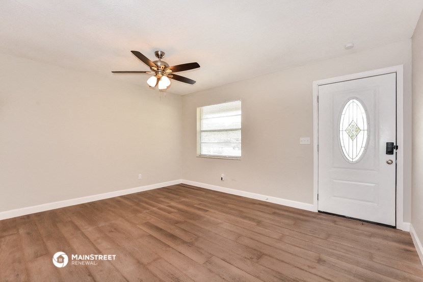 the spacious living room with a ceiling fan and wood flooring