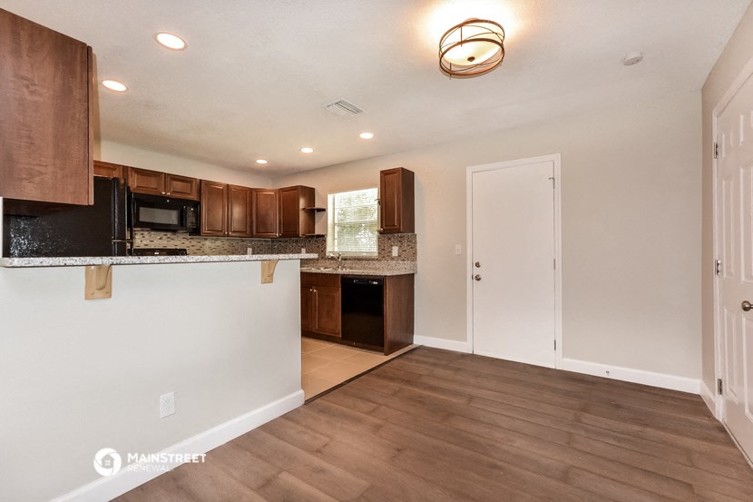 the kitchen and living room of an empty house with wood flooring