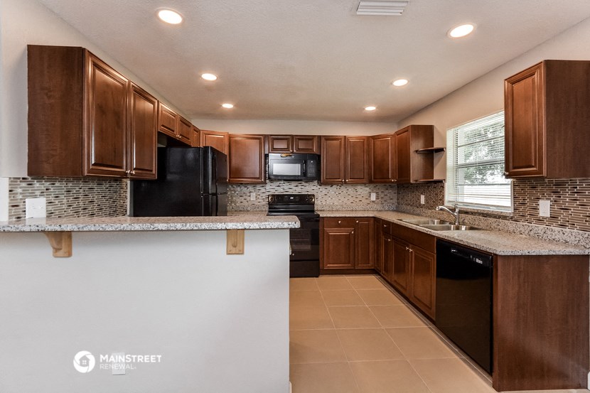 a kitchen with brown cabinets and black appliances and a counter top