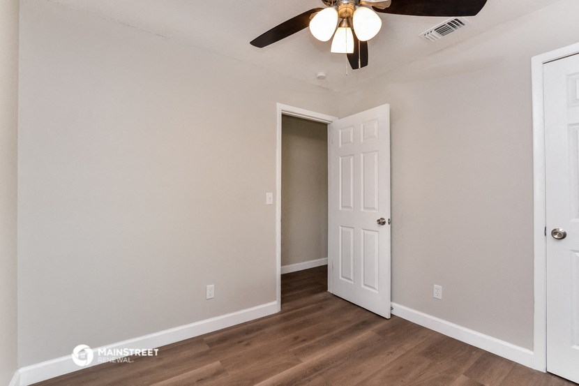 a bedroom with a ceiling fan and a door to a closet