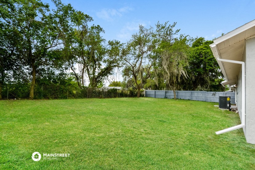 a backyard with a grass lawn and a fence