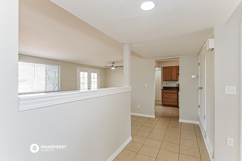 an empty living room with a large window and a kitchen