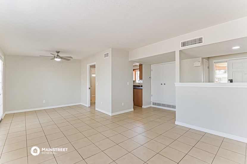 a spacious living room with tile flooring and a ceiling fan