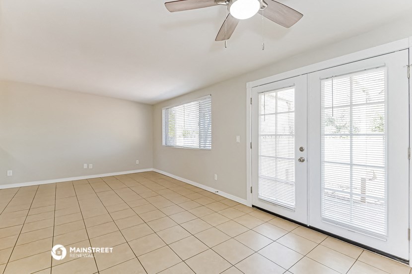 an empty living room with a ceiling fan and doors to a patio