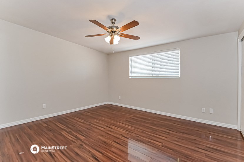 the living room has hardwood floors and a ceiling fan