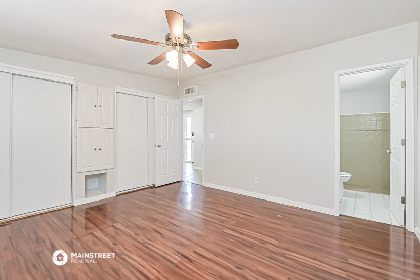 an empty living room with wood floors and a ceiling fan