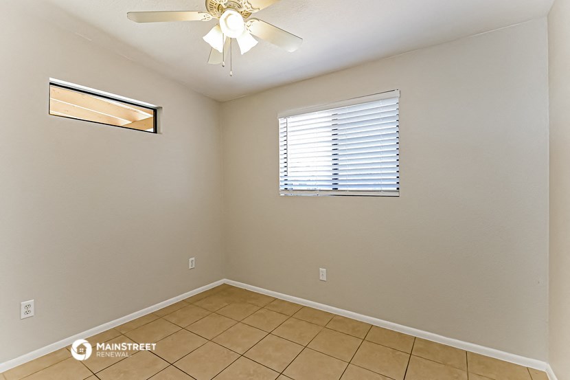 the living room of an empty home with a ceiling fan and a window