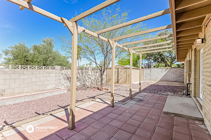 a covered patio with a brick wall and a fence