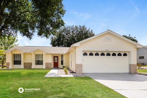 a yellow house with a white garage door and a lawn