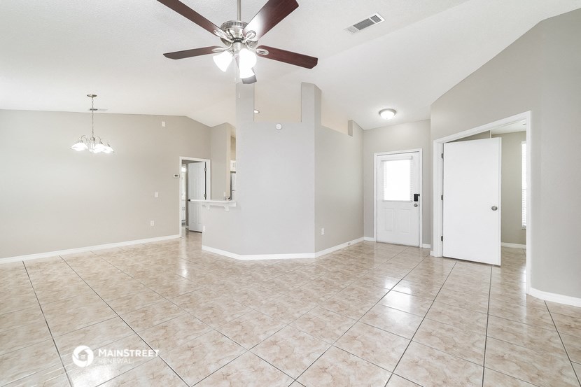 an empty living room with a ceiling fan and a tile floor
