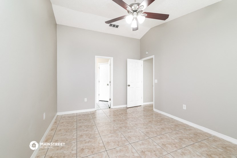 an empty living room with a ceiling fan and a tiled floor