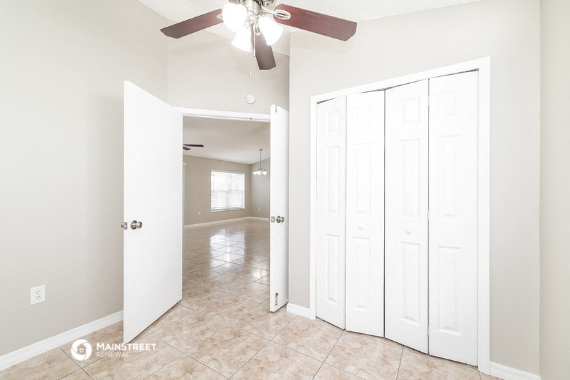 an empty bedroom with white closets and a ceiling fan