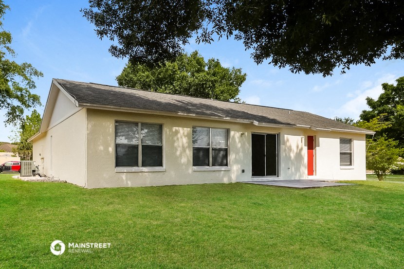 a small white house with a lawn and a tree
