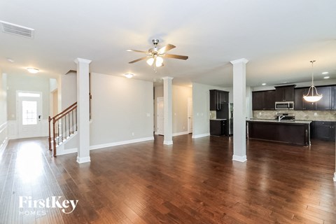 an empty living room and kitchen with a ceiling fan