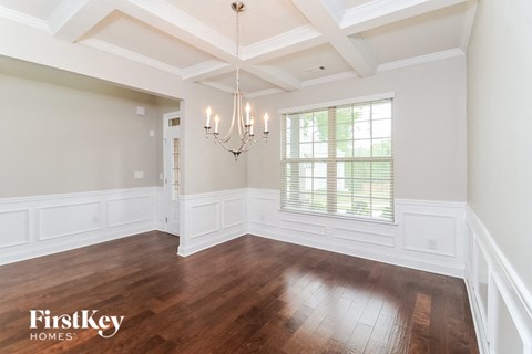 an empty dining room with a chandelier and a window