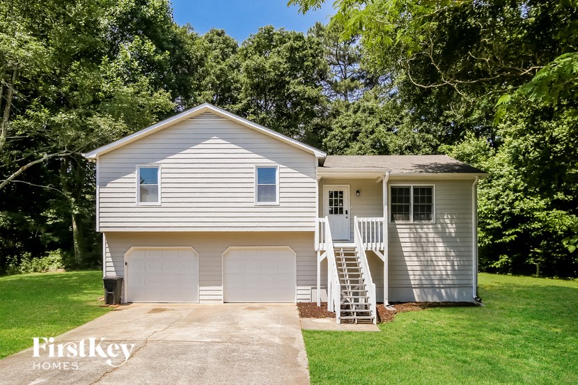 a white house with two garage doors and a staircase