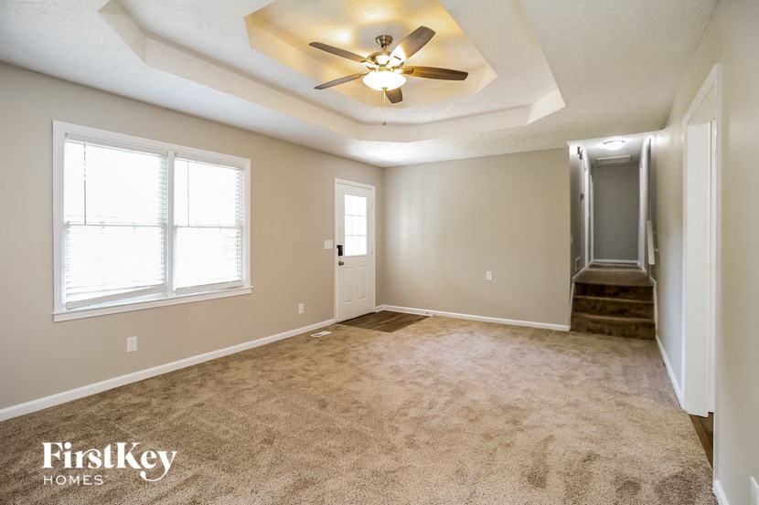 an empty living room with a ceiling fan and a door