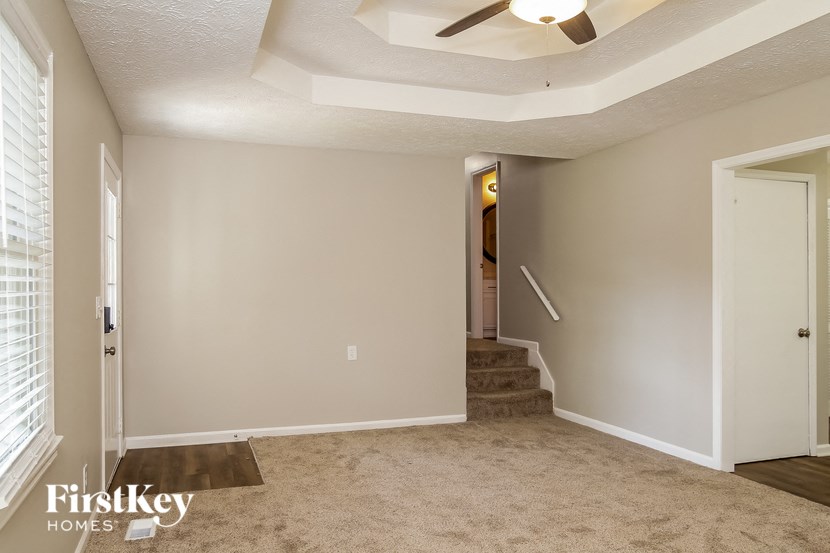 an empty living room with stairs and a ceiling fan