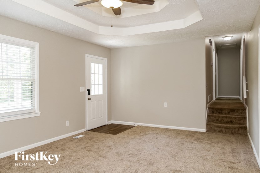 a living room with a ceiling fan and a staircase