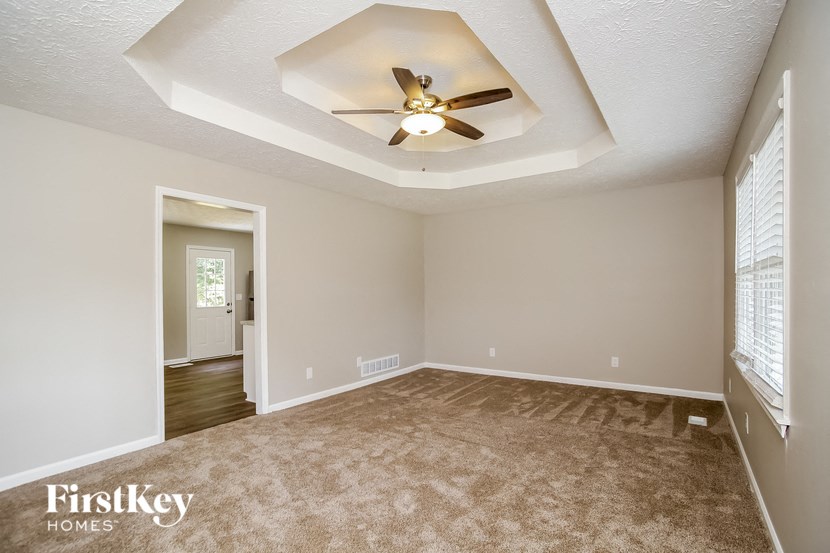 an empty living room with a ceiling fan and a carpet