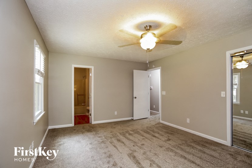 an empty living room with a ceiling fan and a door to a bathroom