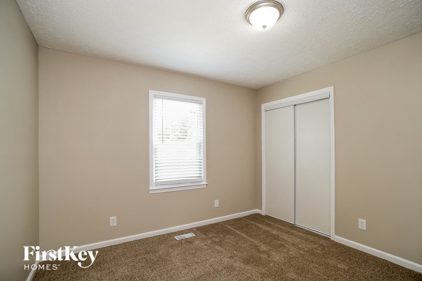 a bedroom with carpet and a door to a closet