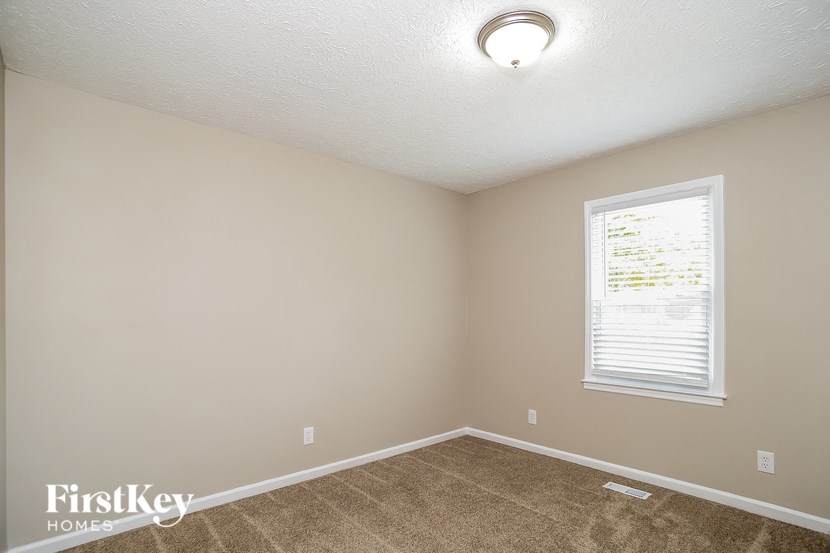 a bedroom with a window and a carpeted floor