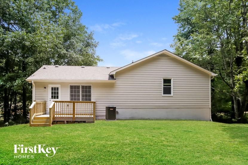 the front of a white house with a deck and a yard
